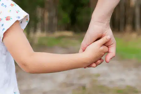 A parent holding a child’s hand shows care linked to child support payment in Montana